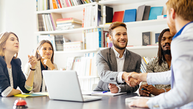 A group of people in a meeting where two men are shaking hands