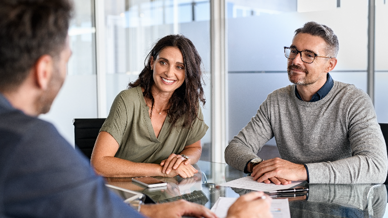 Three people in an office having a meeting at a conference table.