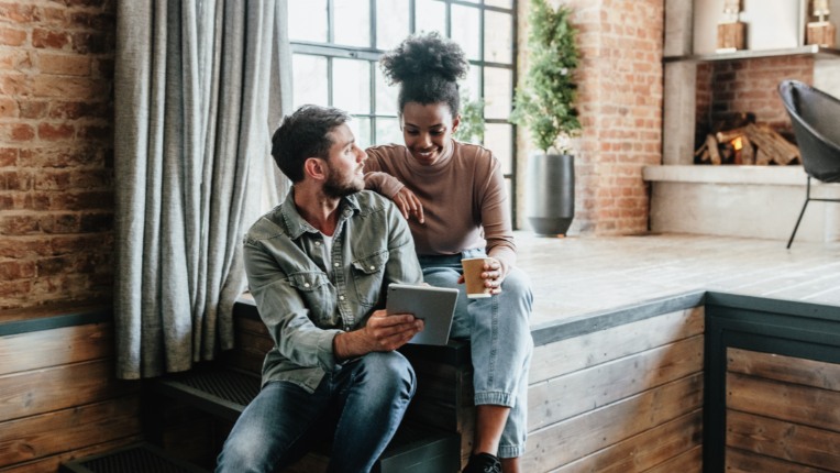 Couple in their home drinking coffee, looking at iPad.